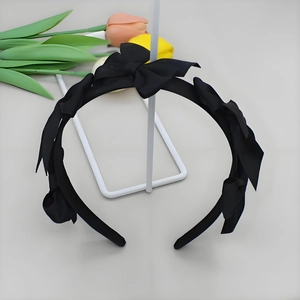 Detail of elegant black headband with layered chiffon bows hanging on a metal rack