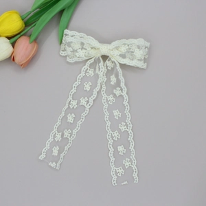 Close-up of elegant white lace bow hair clip with delicate floral embroidery and long ribbons