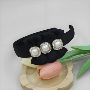Detailed macro of black fabric headband with satin bow and rhinestone pearl accents