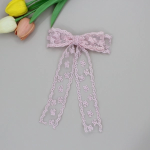 Detail of pink lace bow hair clip featuring delicate floral embroidery and long ribbons