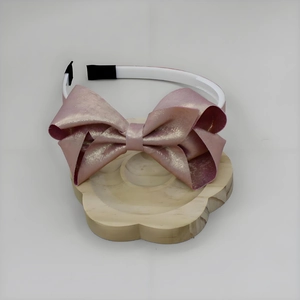 Dettaglio del cerchietto con fiocco rosa a strati con finitura perlata su supporto