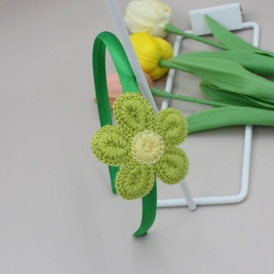 Detalle de diadema de satén verde con girasol de ganchillo para mujeres y niñas