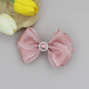 Detailansicht der rosa Satin-Schleife Haarspange mit Rüschenkanten und Strass-Ring-Mitte