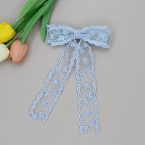 Detail of light blue lace bow hair clip with floral embroidery and long ribbons
