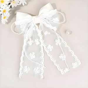 Detailed close-up of white lace bow hair clip with embroidery and pearl chain detail