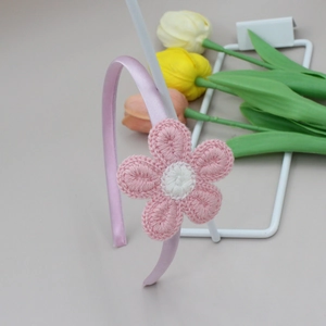Detalle de diadema de girasol de ganchillo rosa sobre un soporte de metal blanco