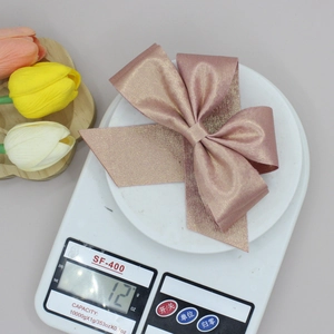 Mesure du poids d'une pince à cheveux nœud rose doré pailleté sur une balance