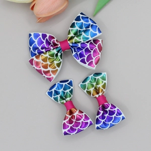 Gros plan de barrettes à nœud motif écailles de poisson arc-en-ciel pour filles