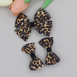 Detail of 3-piece leopard print bow hair clips set on ribbed ribbon fabric textures