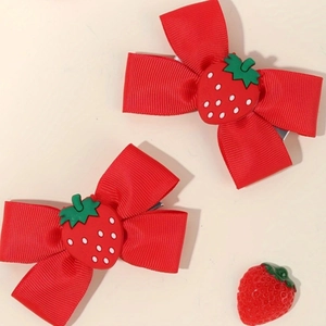 Close-up of red ribbon bow hair clips with cute 3D strawberry charms and metal grip