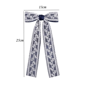 Navy blue satin hair clip with white floral lace layers and long ribbon streamers