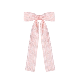 Detailed view of pink lace bow hair clip with elegant floral embroidery and long ribbons