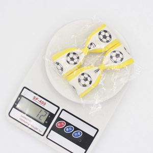 Weight measurement of soccer pattern bow hair clips in clear packaging on a digital scale