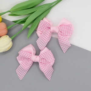Vue détaillée de barrettes à nœuds à carreaux roses montrant la texture du tissu