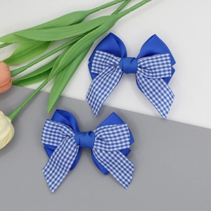 Détail de deux barrettes à cheveux à nœud bleu et motif à carreaux en ruban grain-grain