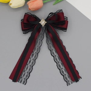 Detail of burgundy satin bow hair clip with black lace trim and sparkling rhinestone center
