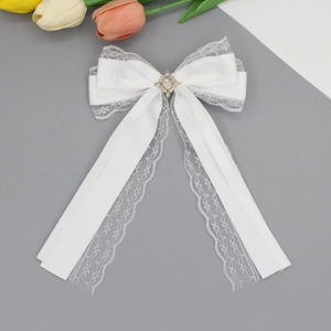 Close-up of white lace bow hair clip featuring a sparkling rhinestone center flower