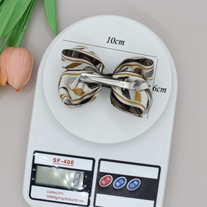 Barrette à cheveux élégante en forme de nœud tissé beige et doré, taille 10cm par 6cm