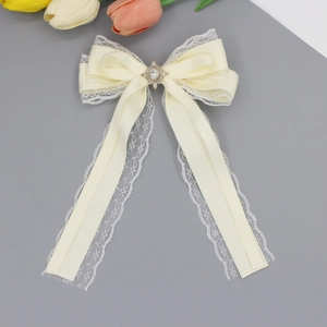 Close-up of elegant cream satin and lace bow hair clip with a rhinestone center detail