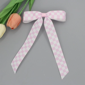 Détail du nœud papillon à carreaux rose et blanc en ruban gros-grain avec rubans