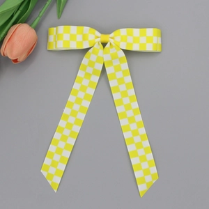 Détail d'une pince à cheveux à carreaux jaunes et blancs avec de longs rubans