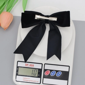 Elegant black velvet swallowtail bow hair clip weighing 10g on a white electronic scale