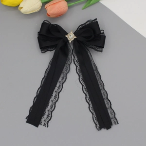 Detail view of black lace ribbon bow hair clip with sparkling gold rhinestone center