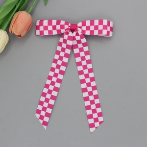 Détail d'une pince à cheveux à carreaux roses et blancs avec de longs rubans élégants