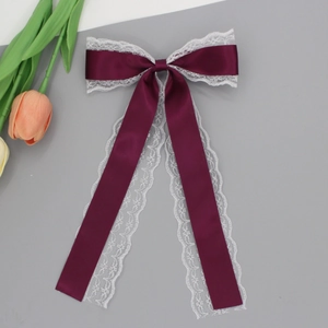 Détail du nœud papillon en soie bordeaux avec dentelle blanche et longs rubans fluides