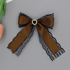 Detailed macro view of coffee brown satin bow clip with black lace and heart gemstone