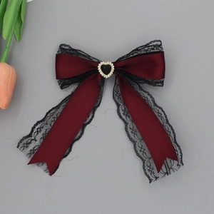 Detailed macro view of burgundy bow hair clip with black lace and heart gemstone