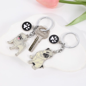 Detail view of pug enamel keychain with paw print charm on white decorative plate