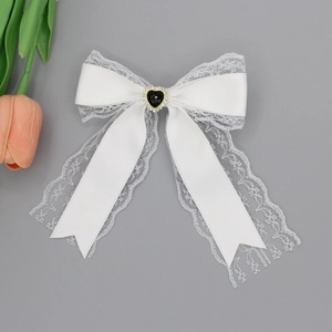 Detailed view of white lace bow hair clip with black heart gemstone and crystal rhinestones