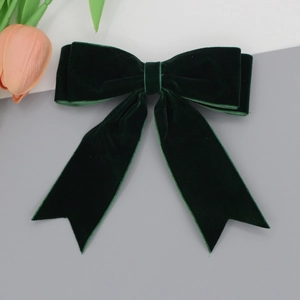 Detail view of the dark green velvet bow hair clip showing texture and long ribbon