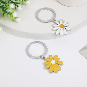 Close-up of elegant metal daisy keychain charms in white and yellow on a display stand