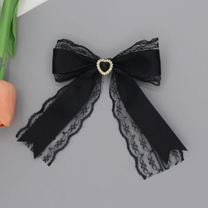 Detailed close-up of a black lace bow hair clip with heart-shaped gemstone center