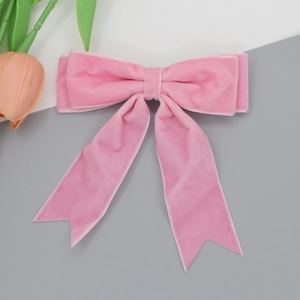 Detailed view of a soft pink velvet bow hair clip with long elegant ribbon tails