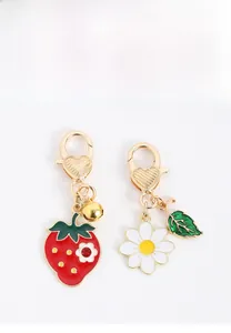 Détail de porte-clés émaillés fraise et marguerite avec fermoir doré en forme de cœur