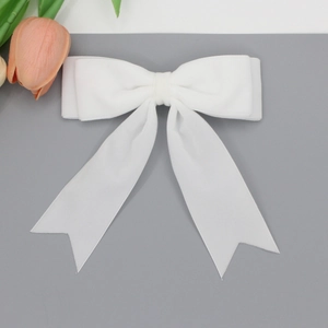 Detail of white velvet bow hair clip with swallowtail ribbons and double-layered wing design
