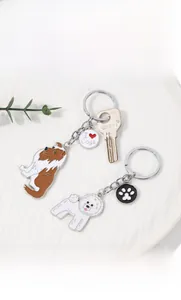 Détail de porte-clés émaillés pour chien avec motifs berger et bichon sur plateau