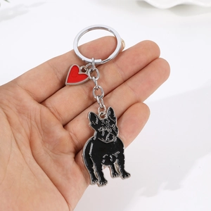 Porte-clés bouledogue français en métal avec cœur rouge tenu sur fond blanc épuré