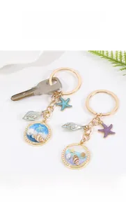 Détail du porte-clés coquillage et étoile de mer avec cadre doré et perle charmante