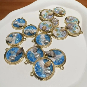 Détail macro du porte-clés conque avec résine bleue, coquillages et perles