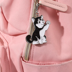 Dettaglio di un simpatico ciondolo per cani in smalto bianco e nero su borsa rosa