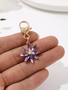Vue détaillée du fermoir mousqueton doré en cœur avec breloque fleur en cristal violet
