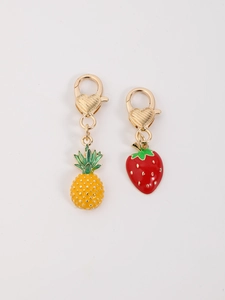 Dettaglio dei ciondoli ananas e fragola in lega con moschettoni a cuore in oro lucido