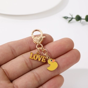 Detail view of cartoon yellow duck LOVE charm with golden lobster clasp for keychains