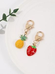 Dettaglio di ciondoli a fragola e ananas smaltati con chiusure a moschettone a cuore