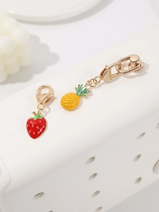 Dettaglio di ciondoli a forma di frutta con fragola e ananas e chiusura a moschettone