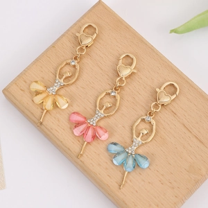 Détail des porte-clés ballerines avec jupes colorées et strass brillants sur fond bois